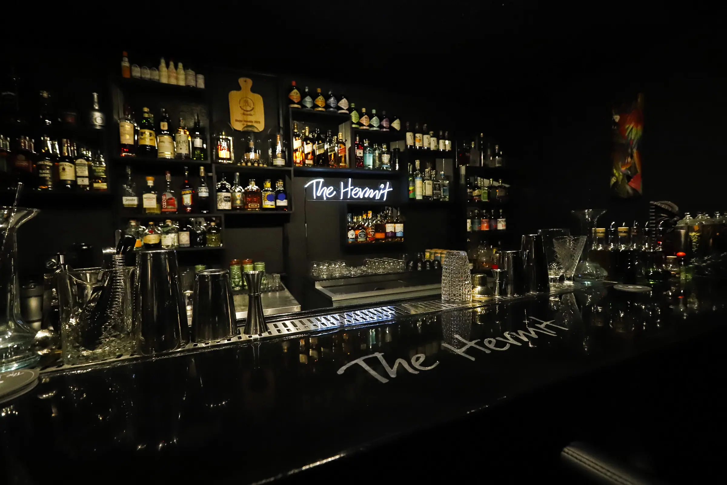The Hermit Cocktail Bar interior with elegant wooden bar counter, ambient lighting and intimate seating area